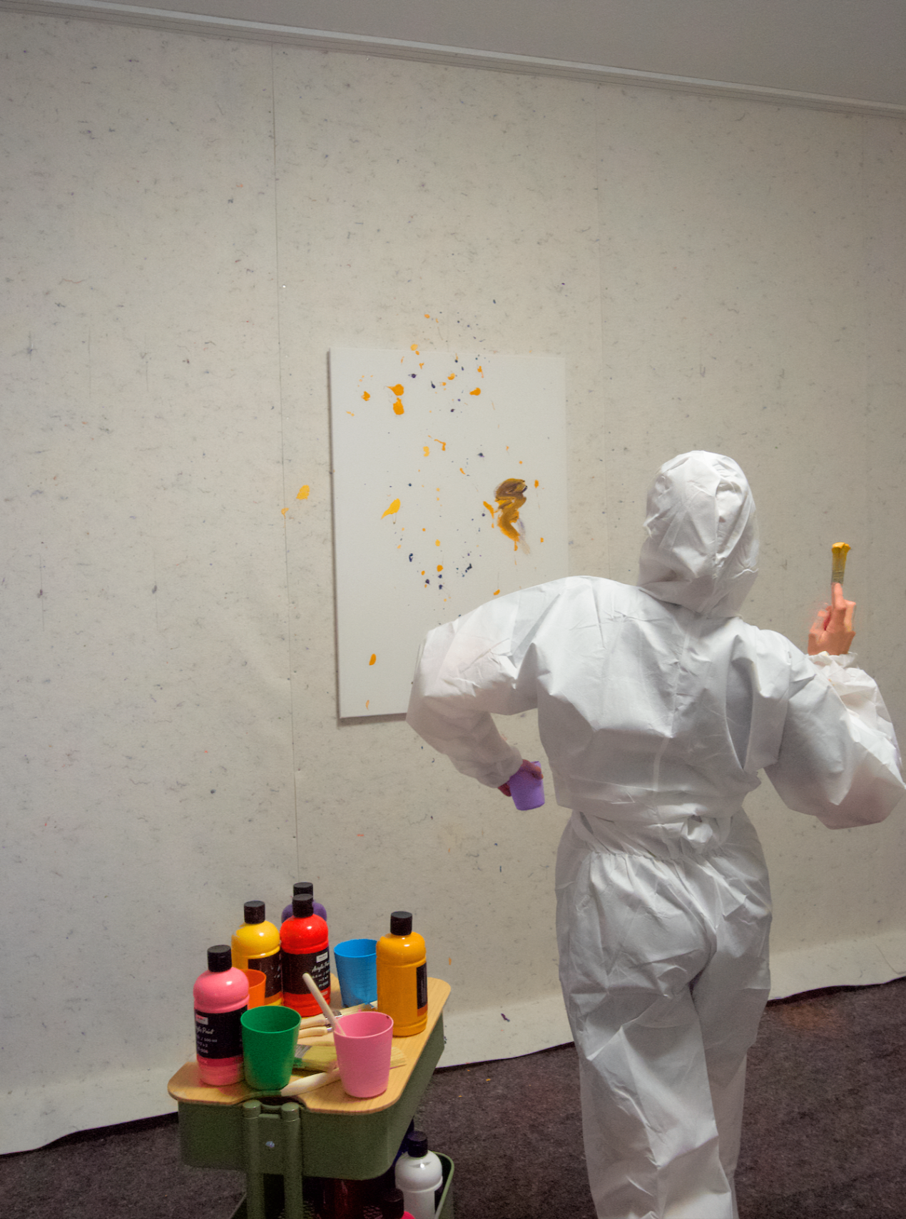 Person im Schutzanzug beim Action Painting an einer Leinwand
